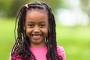 a little girl with braids is smiling for the camera .