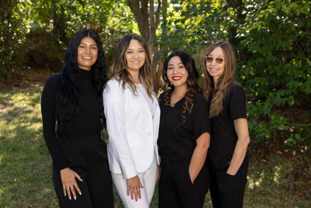 a group of women are posing for a picture together in front of trees .