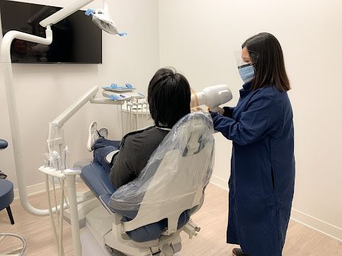 a dentist is taking an x-ray of a patient 's teeth in a dental office .