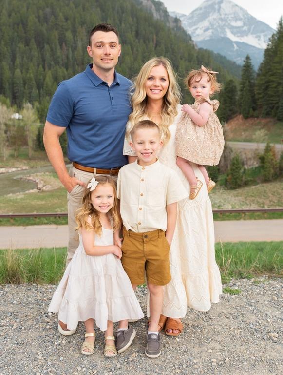a family poses for a picture in front of a mountain .