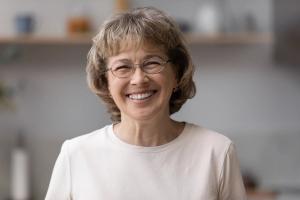 an elderly woman wearing glasses is smiling for the camera .