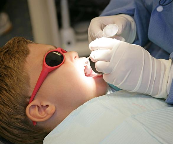 a young boy is getting his teeth examined by a dentist .
