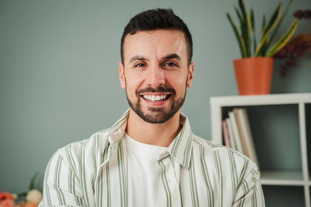 Smiling man with a beard and dark hair in a striped shirt.
