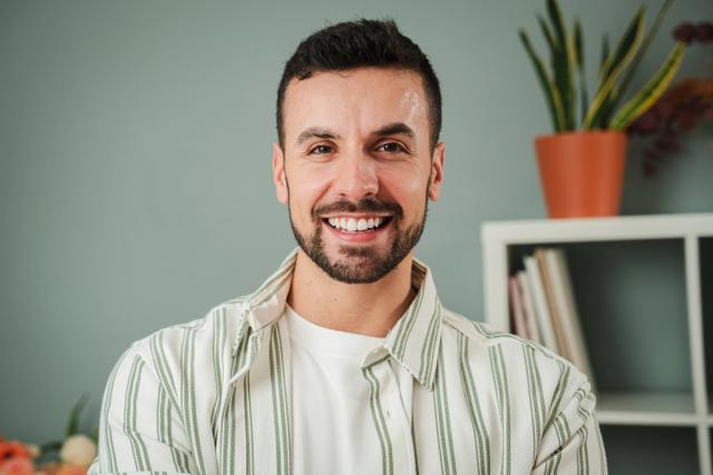 a man with a beard is smiling for the camera while wearing a striped shirt .