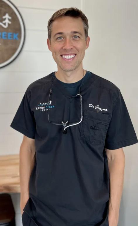 a man wearing a black scrub top with the name dr. jayson on it