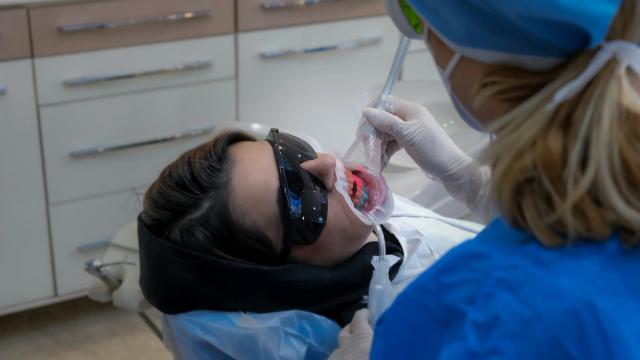 Patient receiving a dental procedure, possibly teeth whitening, from a dental professional.