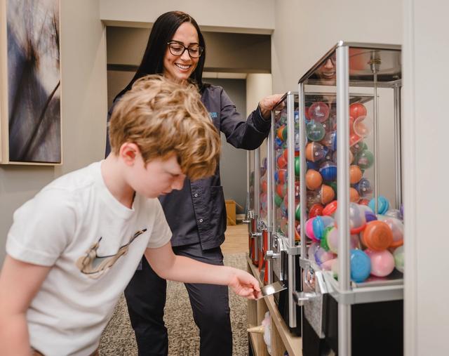 a woman and a boy are playing with a gumball machine .