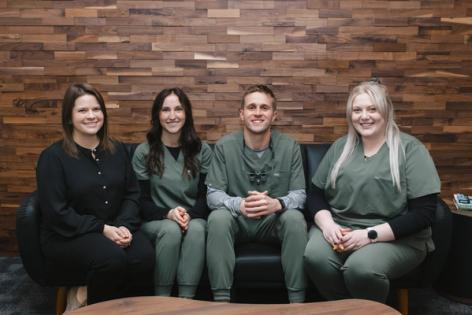 a group of dentists are posing for a picture while sitting on a couch .