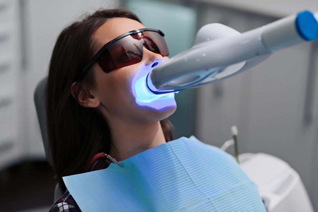 a woman is getting her teeth whitened in a dental office .