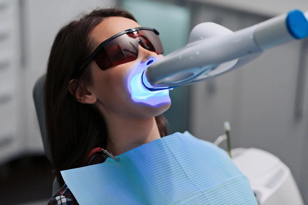 a woman is getting her teeth whitened in a dental office .