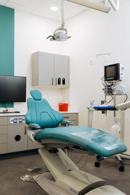 a dental office with a blue dental chair and a monitor