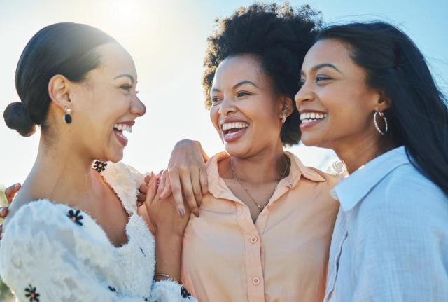 three women are standing next to each other and smiling .