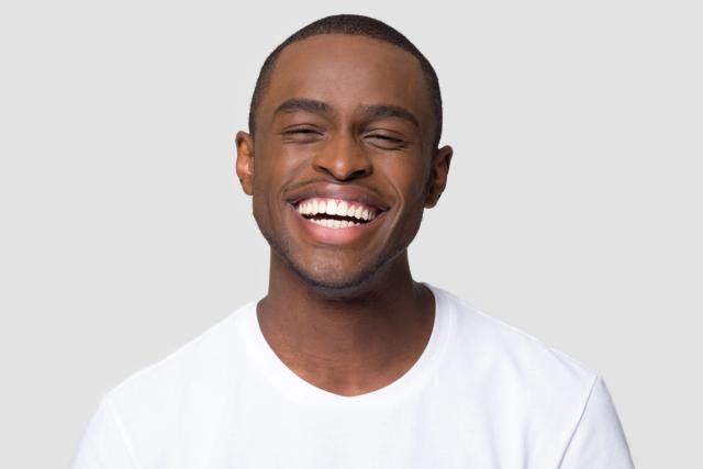 a man in a white t-shirt is smiling with his eyes closed .