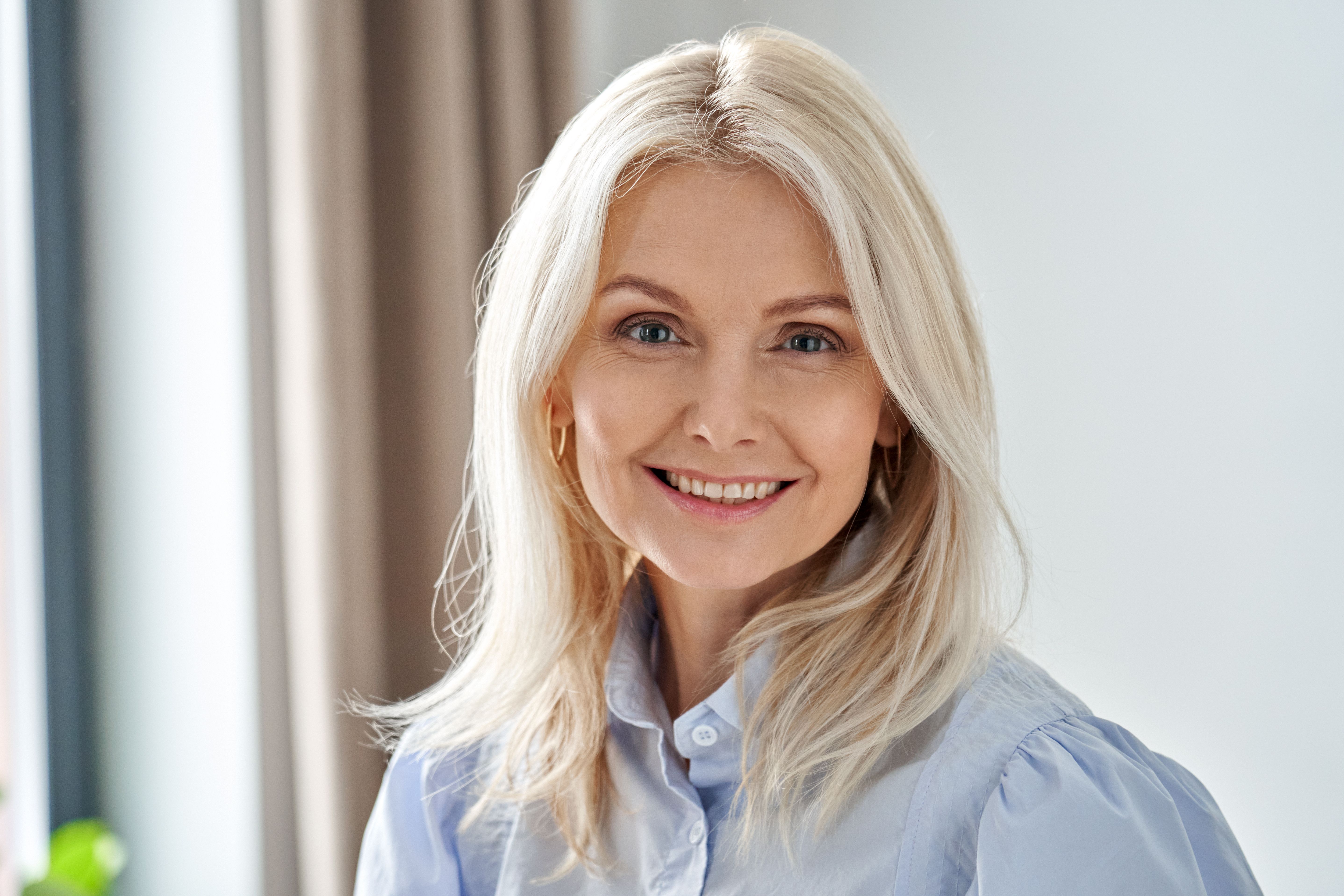 a woman with blonde hair is smiling for the camera while wearing a blue shirt .