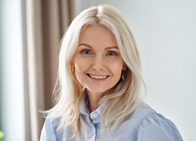 a woman with blonde hair is smiling for the camera while wearing a blue shirt .