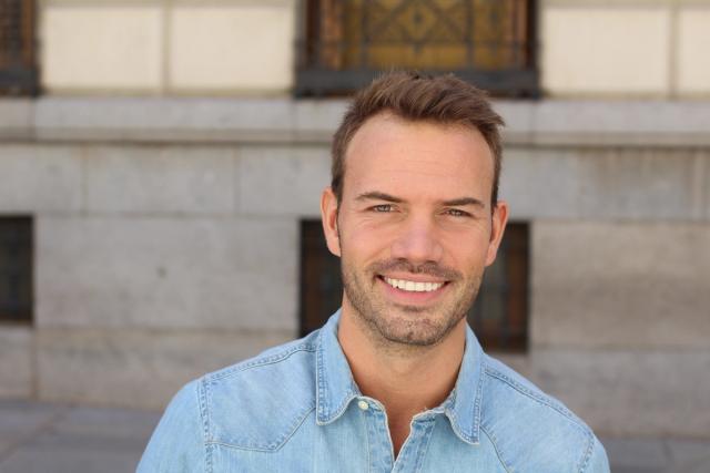 a close up of a smiling man wearing a denim shirt .