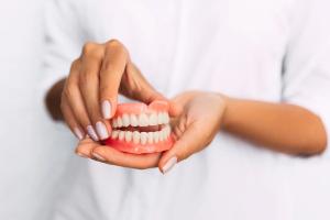 a woman is holding a dentures model of her teeth in her hands .