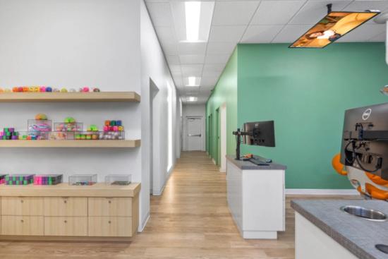 a hallway in a dental office with a desk and two monitors .