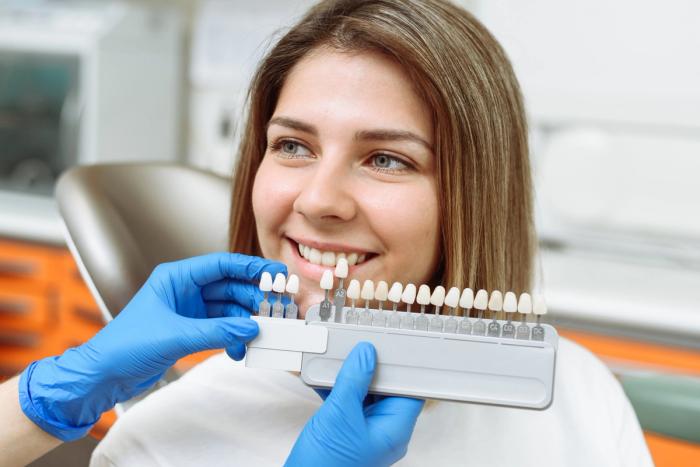 a woman is sitting in a dental chair while a dentist examines her teeth .