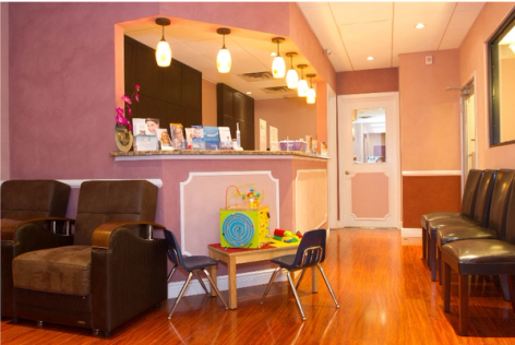 a waiting room with blue chairs and a white counter in a dental office .