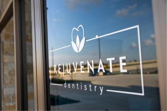 the logo for rejuvenate dentistry is on a glass door .