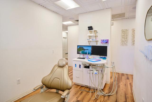 a dental office with a dental chair , desk and computer .