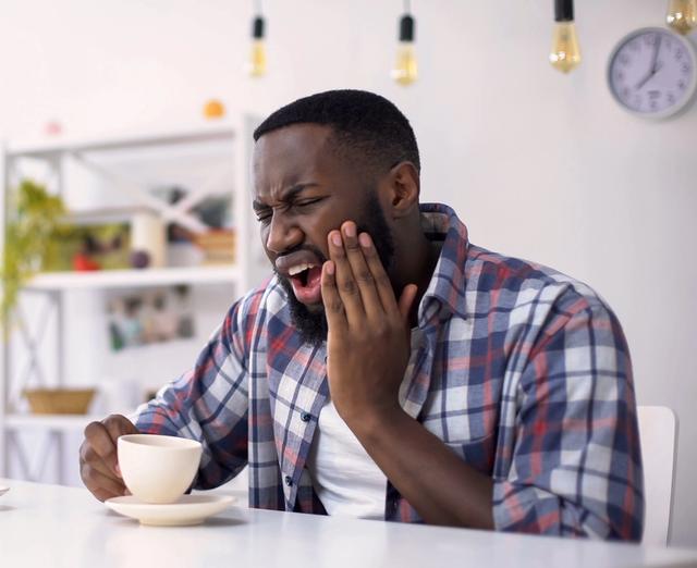 a man is sitting at a table with a cup of coffee and a croissant .