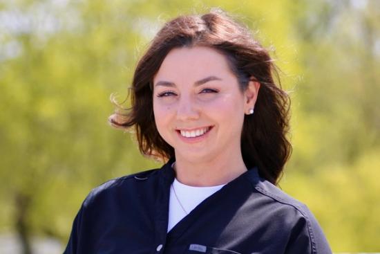 a woman in a black scrub is smiling for the camera .