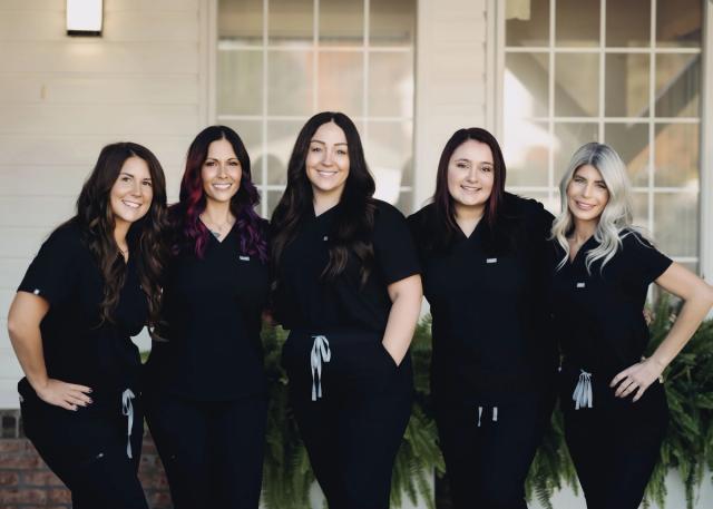 a group of women in scrubs are posing for a picture in front of a building .