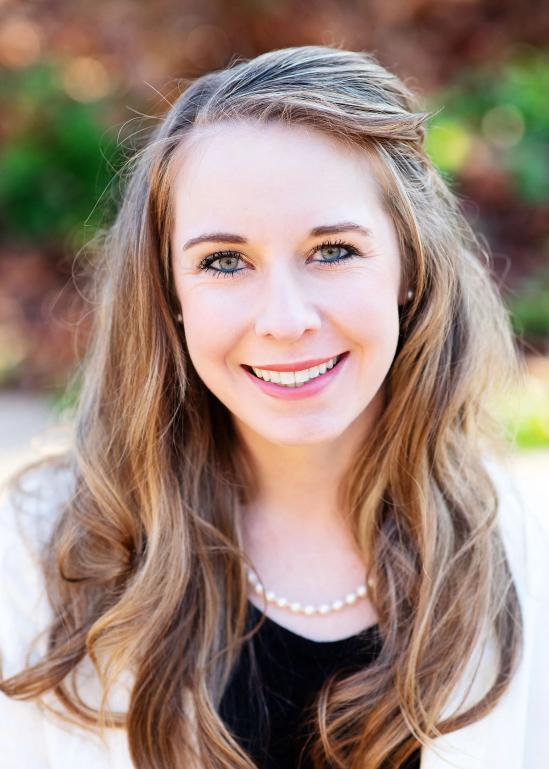 a woman with long hair is smiling and wearing a pearl necklace