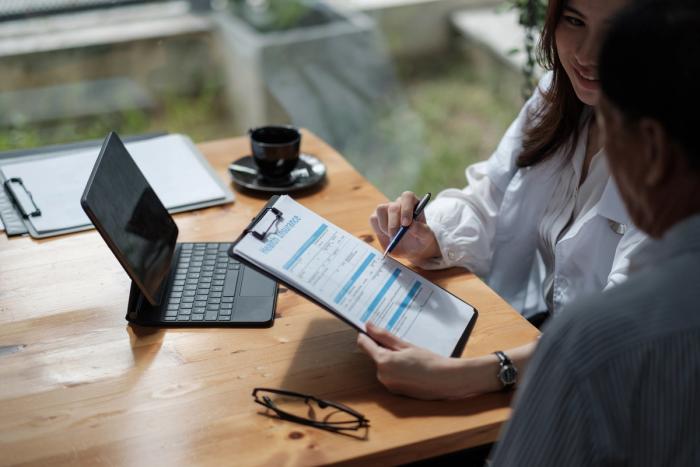 a man and a woman are sitting at a table looking at a resume .