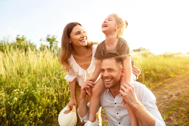 a man is carrying a little girl on his shoulders in a field .