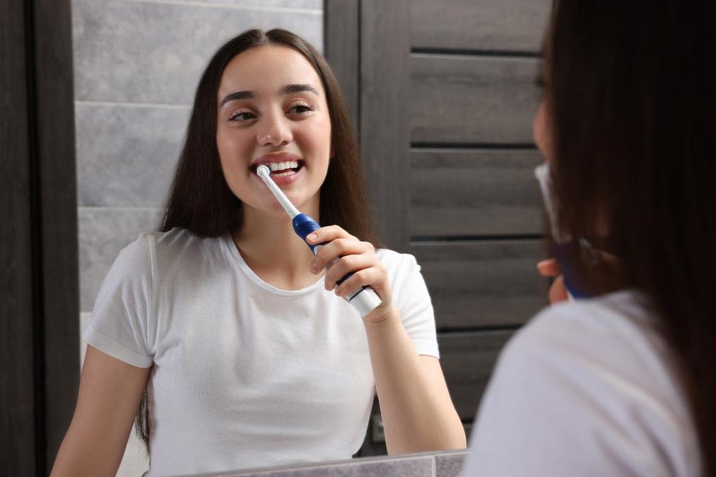 a woman is brushing her teeth in front of a mirror in a bathroom .
