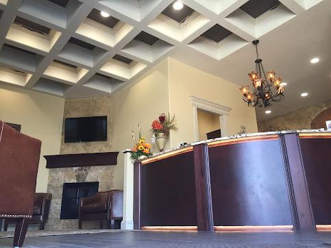 a reception area in a hotel with a fireplace and a chandelier .
