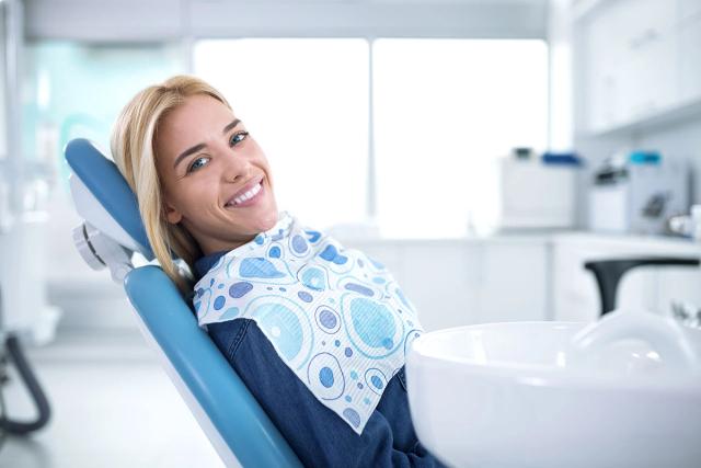 a woman is smiling while sitting in a dental chair .