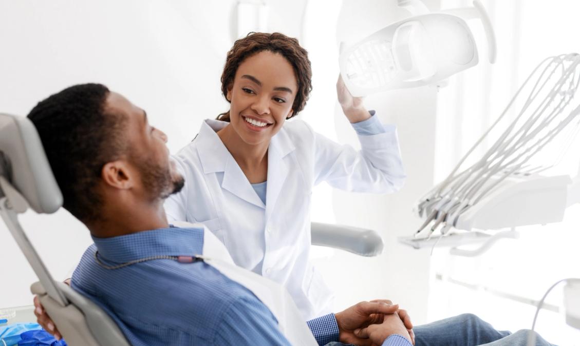 a dentist is talking to a patient in a dental chair .