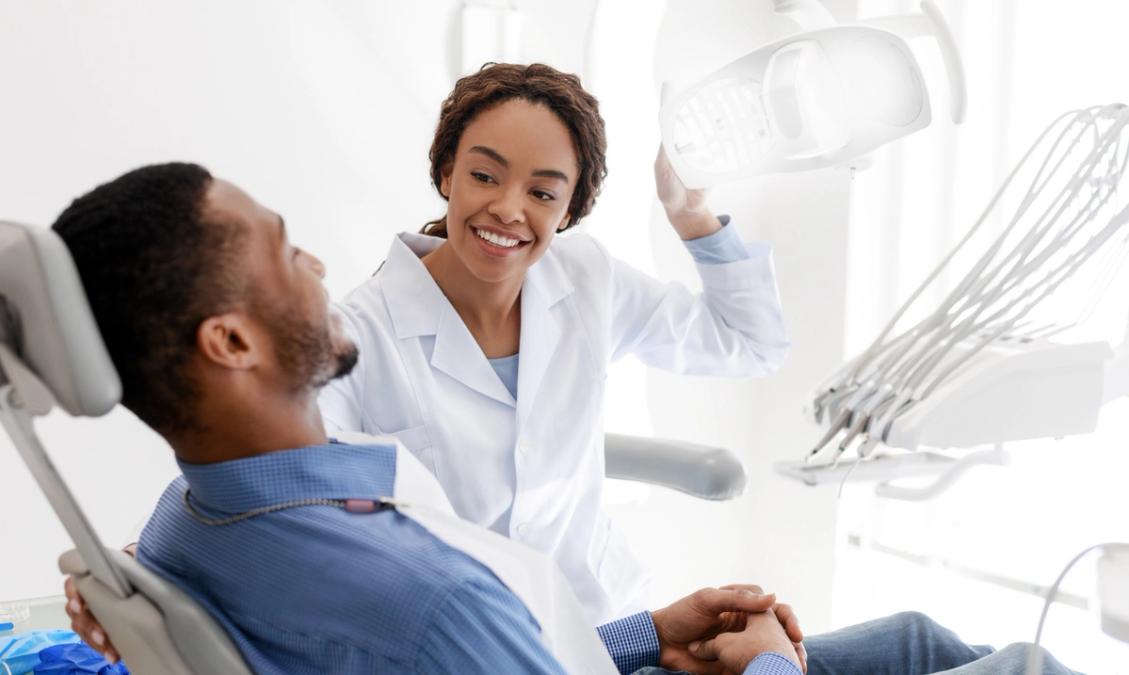 a dentist is talking to a patient in a dental chair .
