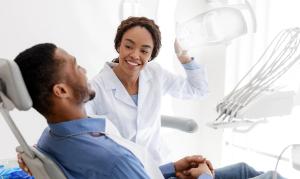 a dentist is talking to a patient in a dental chair .