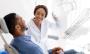 a dentist is talking to a patient in a dental chair .