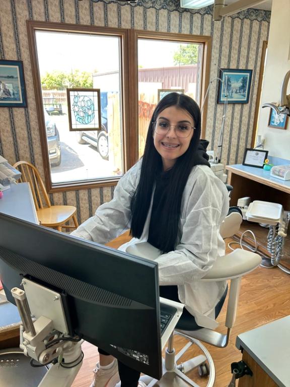 a woman with braces sits in front of a computer monitor