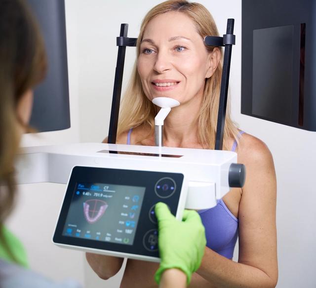 a woman is getting an x-ray of her teeth in a dental office .