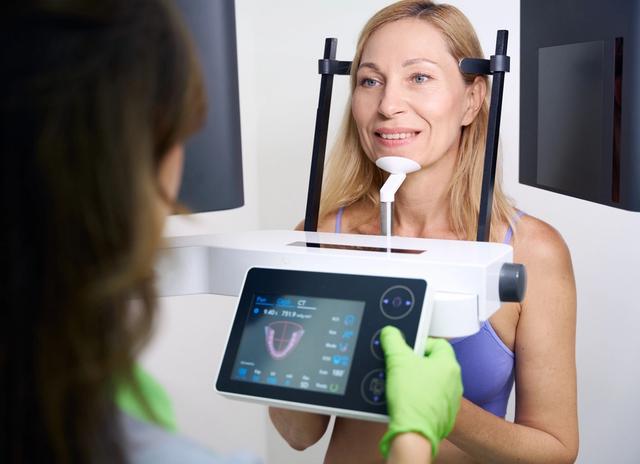a woman is getting an x-ray of her teeth in a dental office .