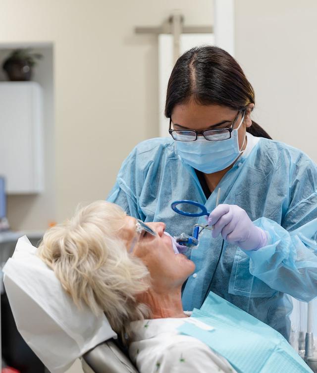a dentist examines a patient 's teeth with a magnifying glass