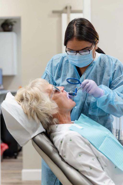 a dentist examines a patient 's teeth with a magnifying glass
