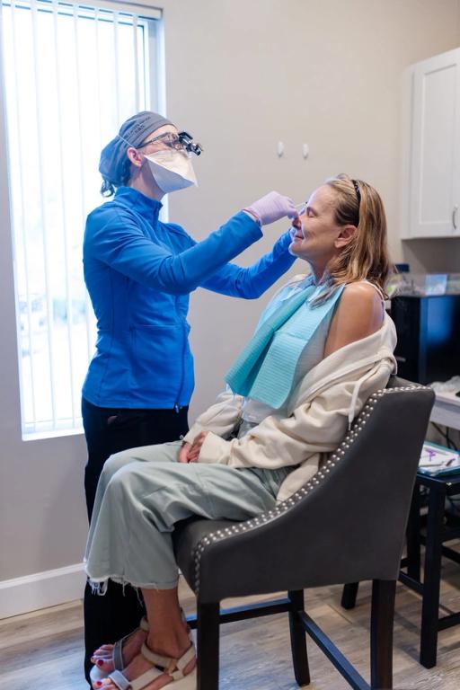 a woman is getting her teeth examined by a dentist