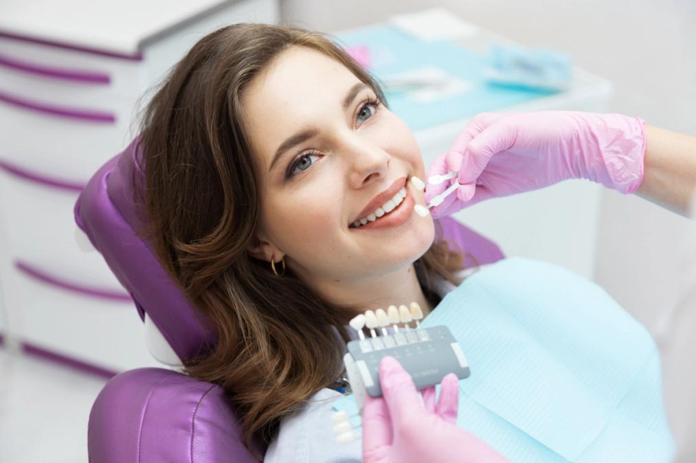 A woman smiling as a dental professional matches her tooth shade.