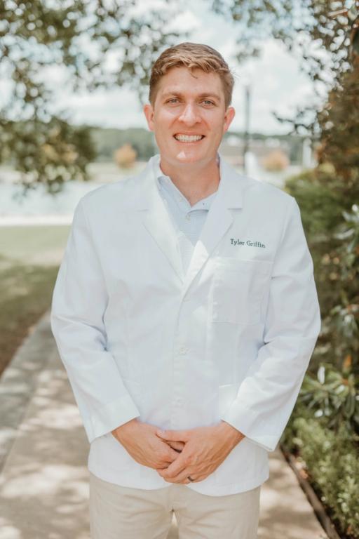 a man wearing a white coat with the name tyler griffin on it