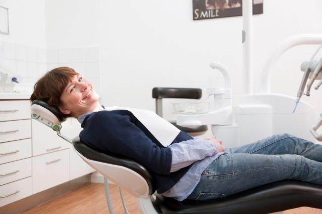 a woman is laying in a dental chair and smiling .