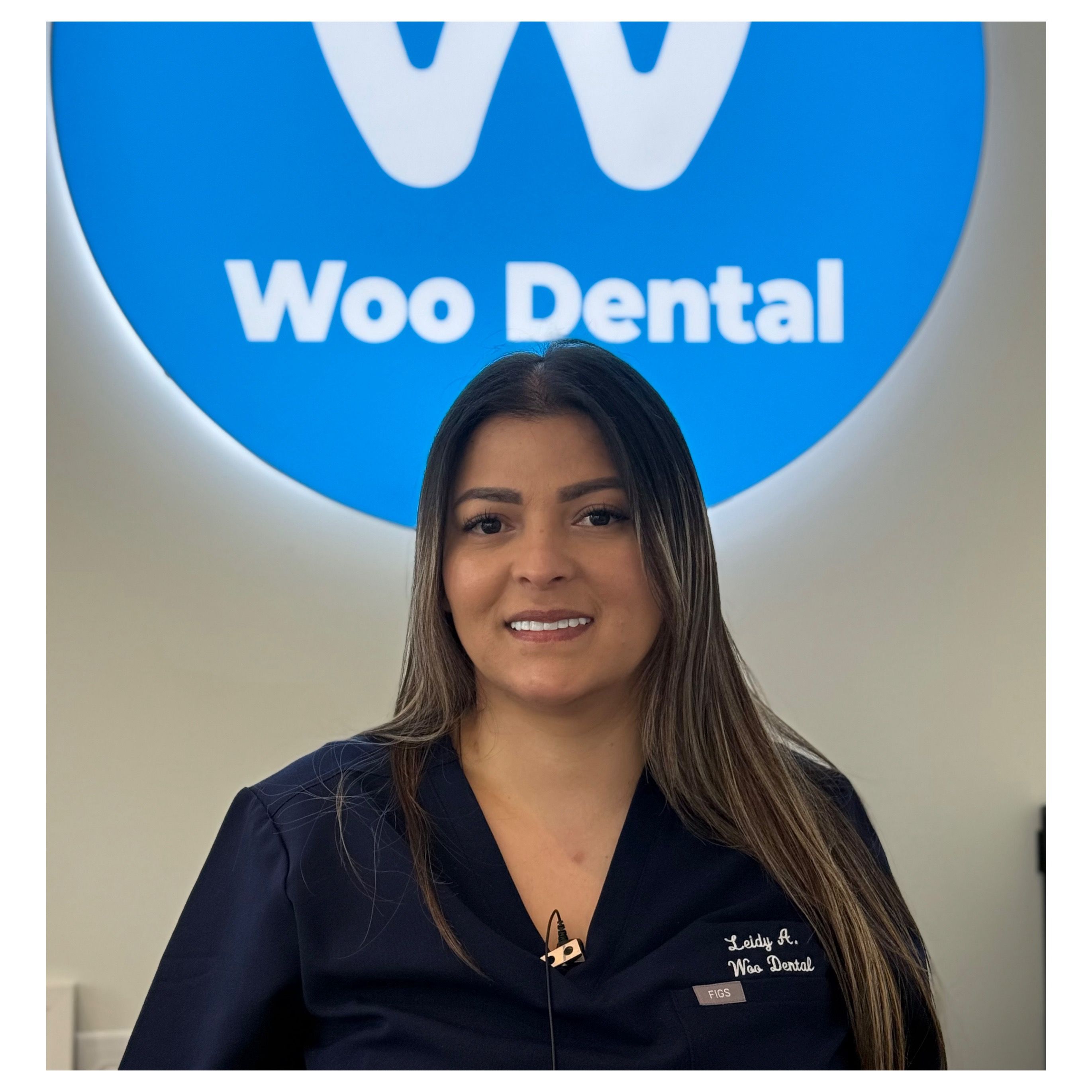 a woman is standing in front of a blue sign that says woo dental .