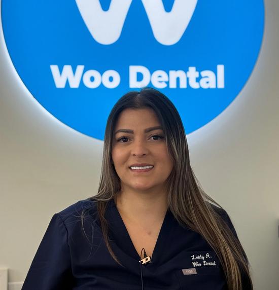 a woman is standing in front of a blue sign that says woo dental .